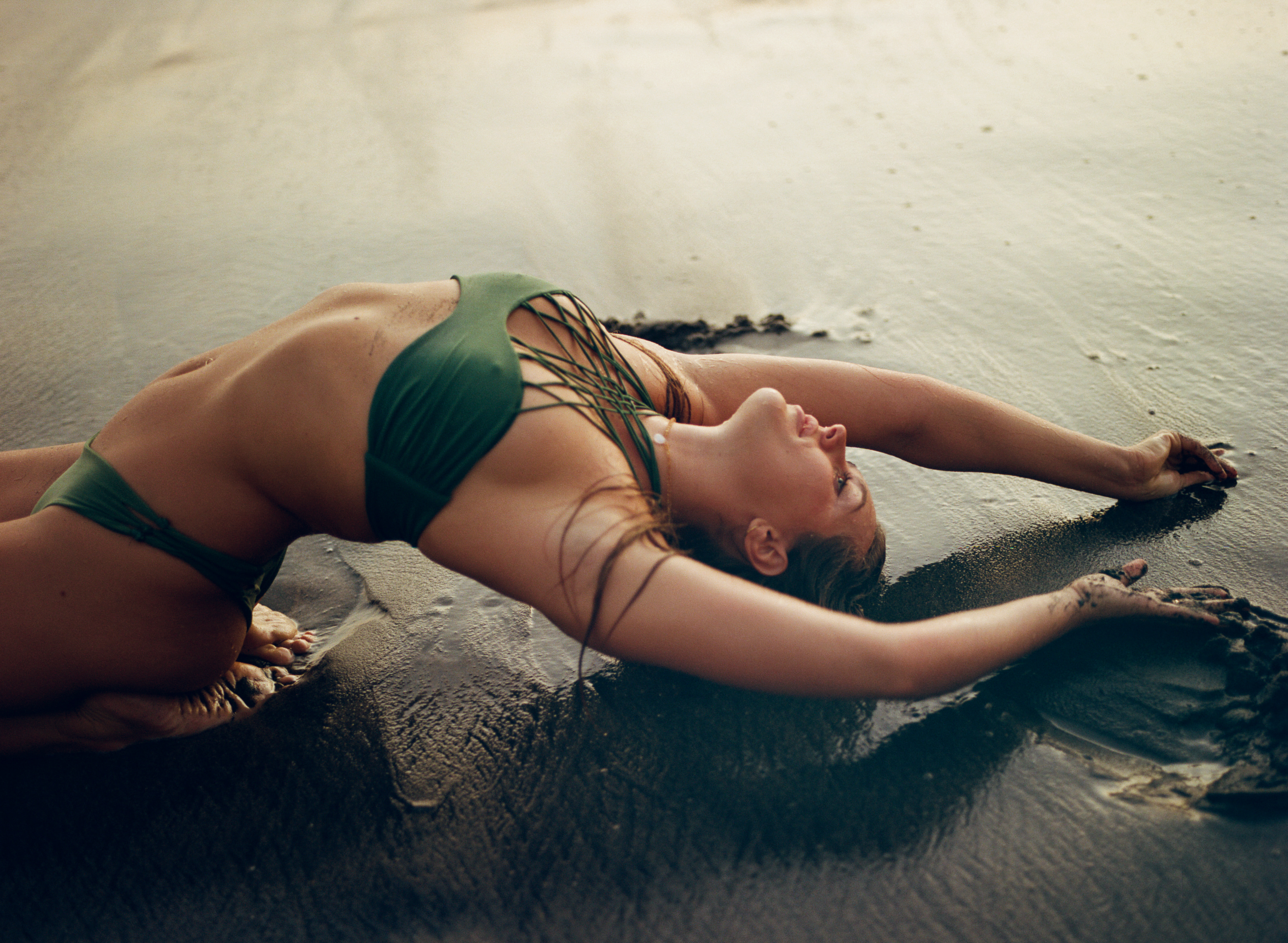 Alaya arched back over the wet sand at golden hour, arms reaching behind her, ocean light on her skin